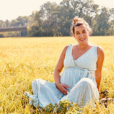 Portrait von Annegret Kalunka mit Babybauch auf grüner Wiese